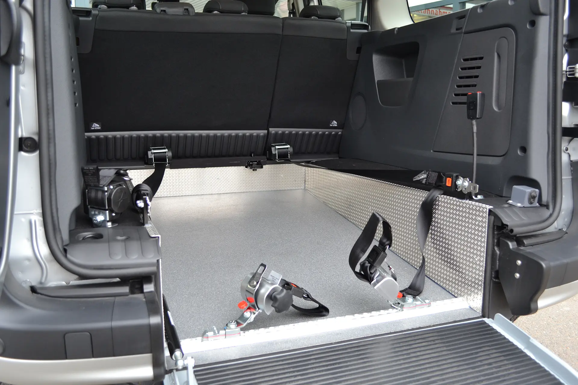 Rollstuhlsicherung im Fahrzeug mit Kraftknotenadapter und Vierfachfitting-Bodenverankerung