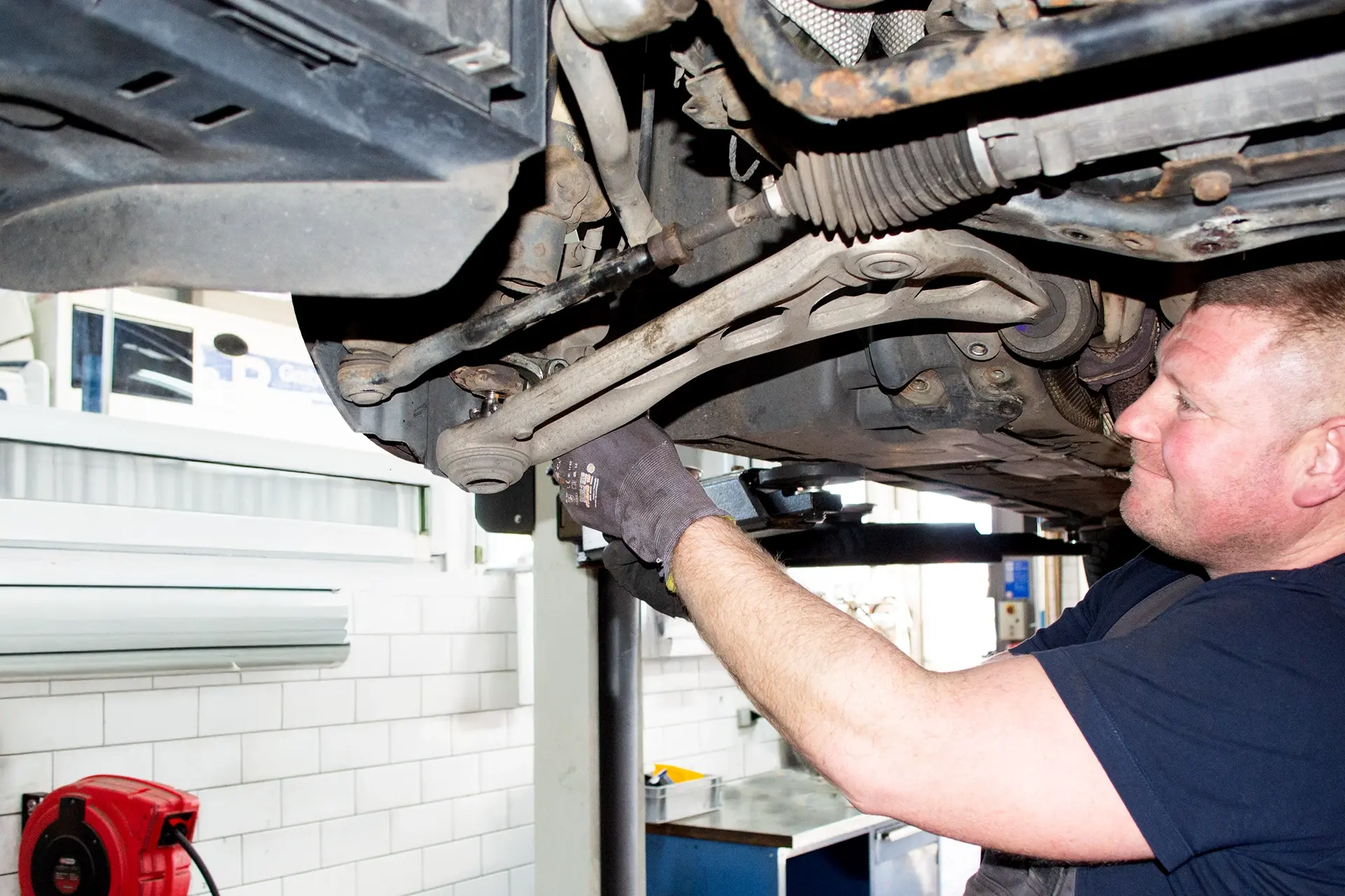 Prüfung des Querlenkers am Fahrzeugfahrwerk durch einen Mechaniker in der Werkstatt Dörfelt Zwickau